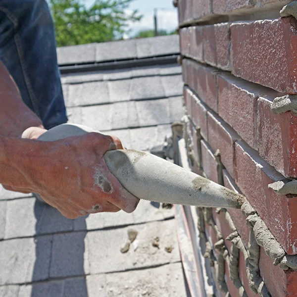 Professional mason performing tuckpointing work on brick wall in Michigan